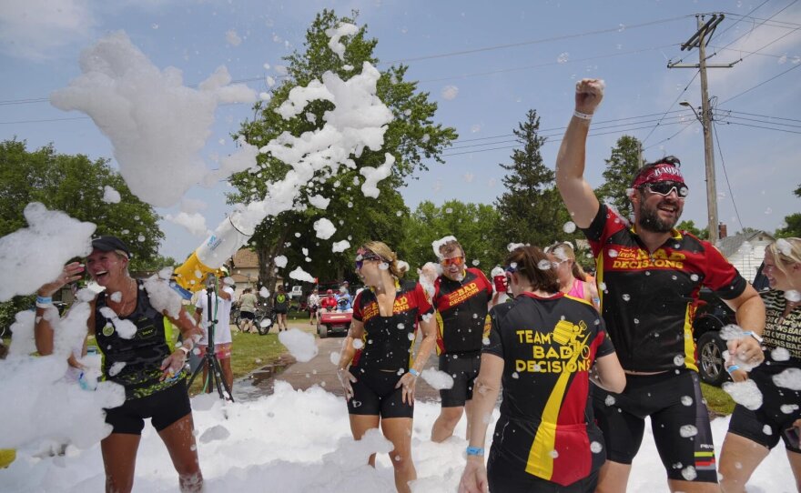 Riders, participating in RAGBRAI 50, dance in a foam sprayer in Washta on Sunday, July 23.