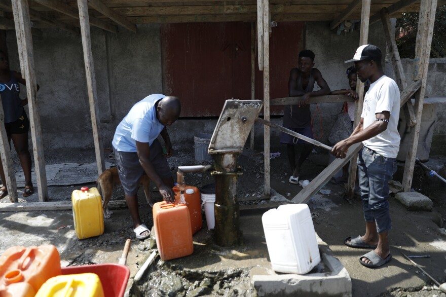 Louisiana Francilo (left) and Wilky Deranci pump water from a public well in Limonade, Haiti, on March 17, 2024.