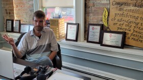 News editor and co-publisher Will Brumleve sits at his desk at the Ford County Chronicle in front of awards and text from the First Amendment. He and co-founder XXXX launched the newspaper in Paxton, Illinois, in 2020, one of the few new papers in the U.S. in recent years.