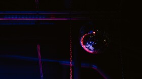 A disco ball hangs over the stage at xBk, a live music venue in Des Moines. It's washed in purple light. 