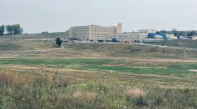 There is a large building nestled into a series of rolling hills.