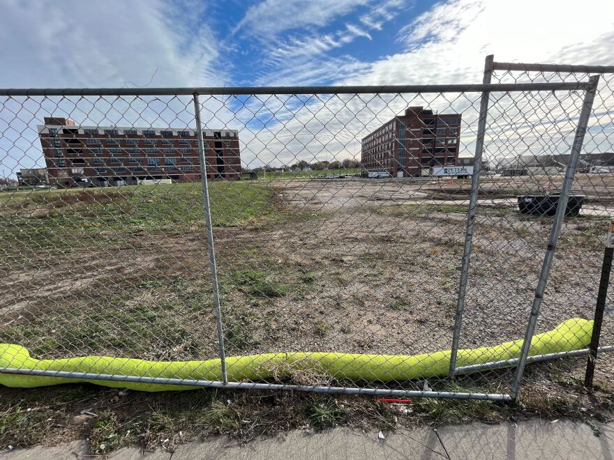 Two brick buildings behind a fenced-off lot.