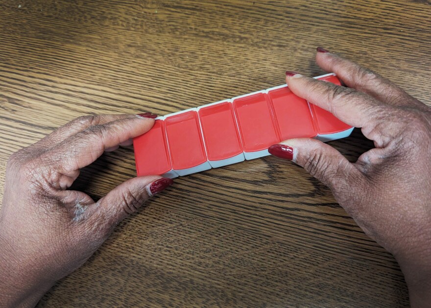 Closeup photo of a woman's hands holding a weekly pill container.