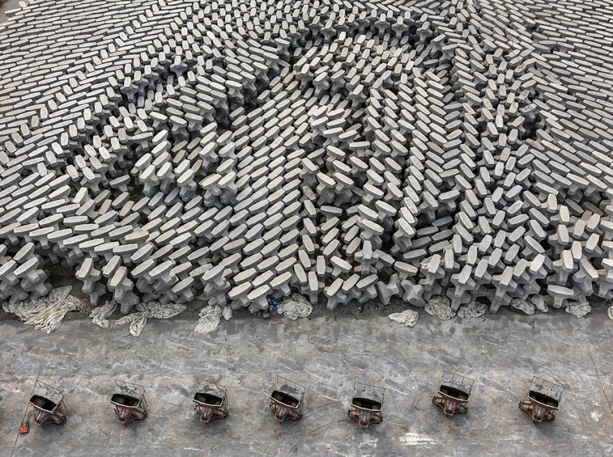 A tetrapod factory in Dongying, China. These concrete blocks are dropped into the ocean to create a barrier that protects low-lying oil refineries from rising sea levels. According to a recent <a href=aad2622__scientific.html review</a>, human beings have now produced enough concrete to cover the entire globe in a 2-millimeter thick layer.