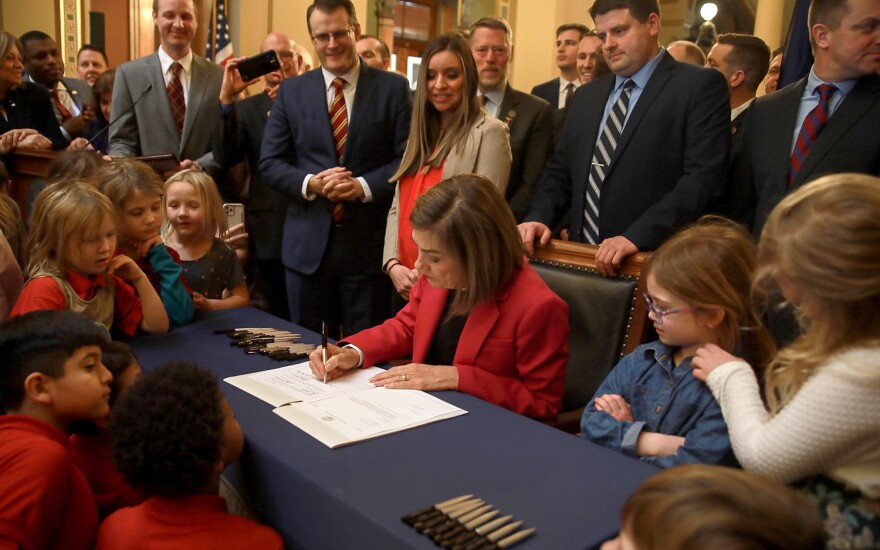 Gov. Kim Reynolds signs the Students First Act in the Capitol rotunda.