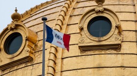 Iowa's flag flapping near the gold dome of Iowa's Capitol.