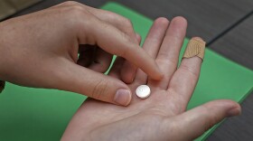 A patient prepares to take the first of two combination pills, mifepristone, for a medication abortion during a visit to a clinic in Kansas City, Kan., on Oct. 12, 2022.