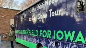 Theresa Greenfield stands with her campaign bus.