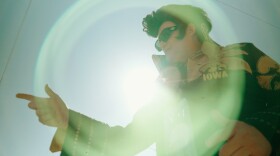 A man stands dressed as Elvis Presley while also wearing University of Iowa attire