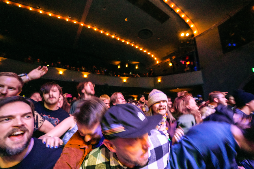 A crowd at the front of the barricade lurches at a concert.