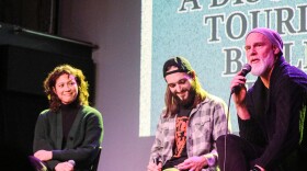 Three panelists smile on stage.