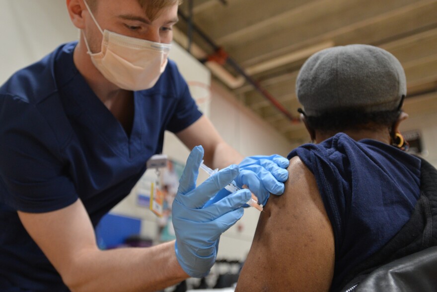 LPN Brice Headrick injects Anita Haney, 74, who showed up at Linwood YMCA for her first COVID-19 vaccination on Feb. 3.