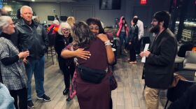 Two women embrace while several watch the emotional gesture.