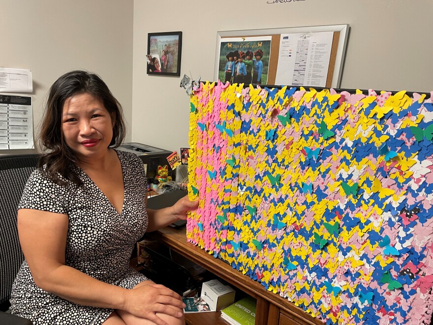 Samantha Huynh holds a board full of paper butterfly cutouts. Each one represents one thousand refugees in the U.S. She and her entire family are represented on the board. They originally came from Vietnam, but fled during the war.