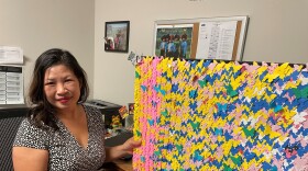 Samantha Huynh holds a board full of paper butterfly cutouts. Each one represents one thousand refugees in the U.S. She and her entire family are represented on the board. They originally came from Vietnam, but fled during the war.