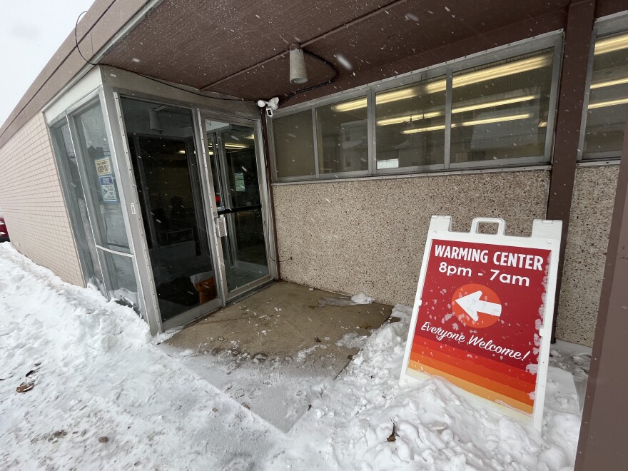 Warming center entrance with sign posting open hours, 8 p.m. to 7 a.m.