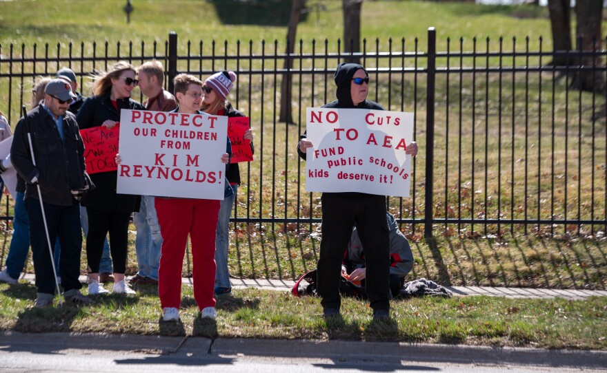 Protesters stand outside the Capitol calling for no cuts to AEA funding.