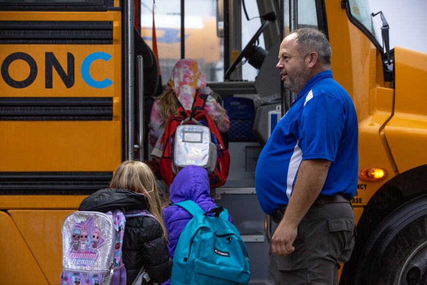 Eric Joiner, transportation supervisor for the Ralls County School District, watches as kids board an electric school bus on Monday, Nov. 20, 2023, in Center, Mo. While most of the district’s buses are powered by gas or diesel, it has recently added two electric school buses to its fleet. The buses were obtained via Inflation Reduction Act grants, intended to introduce electric buses to rural school districts. 