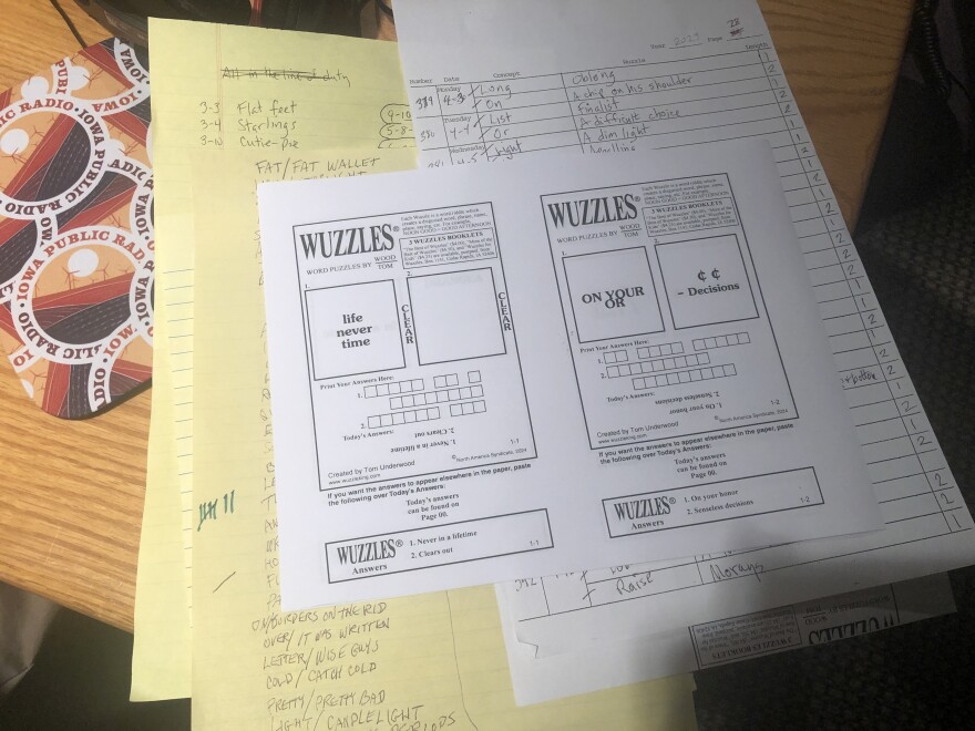 Two pages of puzzles are open on a table, on top of lists of ideas