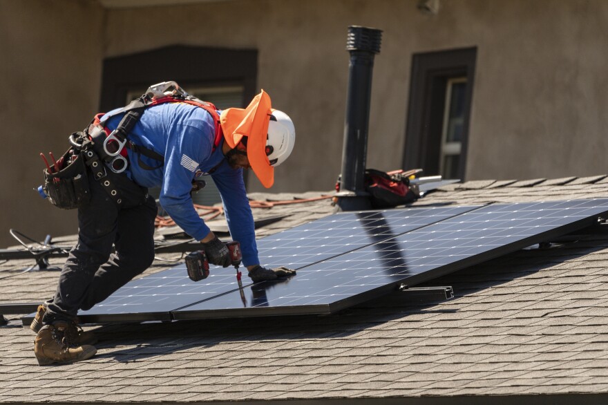 SunPower Corp. solar panels technician Jose Arrechiga braves the extreme heat as he installs solar panels on a residence's roof in Pasadena, Calif., Wednesday, July 19, 2023. The European climate agency calculates that 2023 was the hottest year ever recorded globally.