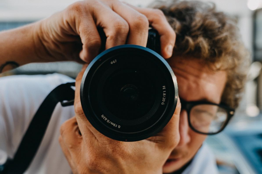 Photographer Britton Hacke holds a camera and takes his own picture in a mirror.