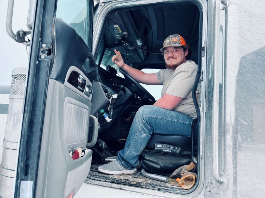 Man is smiling behind the wheel of a semi truck