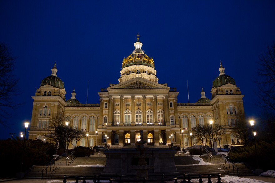 The Iowa Capitol is lit up in front of a dark blue night sky.