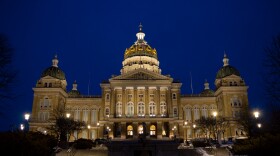 The Iowa Capitol is lit up in front of a dark blue night sky.