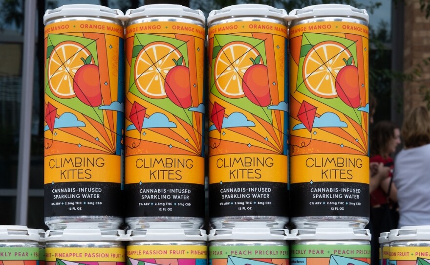 Colorful cans of Climbing Kites social beverage sit in a stack on a table at the Des Moines Arts Fest 2023. 