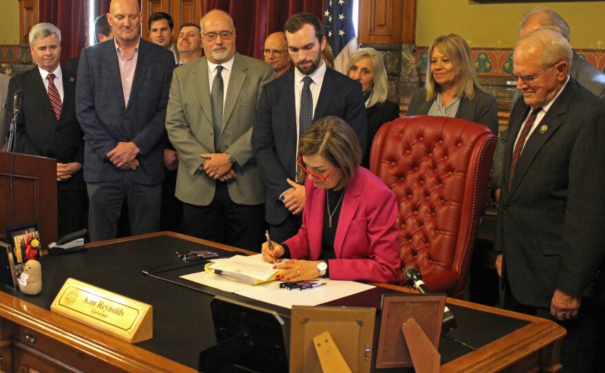 Kim Reynolds signs the AEA bill.