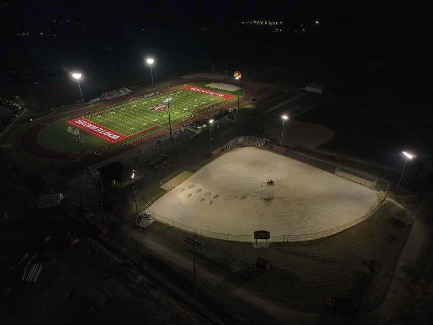 A football field, top, and baseball field under construction are lit up at Whitewater High School Friday, Oct. 1, 2021, in Whitewater, Wis. A growing number of school districts in the U.S. are using federal pandemic funding on athletics projects. When school officials in Whitewater, Wis learned they would be getting $2 million in pandemic relief this year, they decided to set most of it aside to cover costs from their current budget, freeing up $1.6 million in local funding that’s being used to build new synthetic turf fields for football, baseball and softball. (AP Photo/Morry Gash)