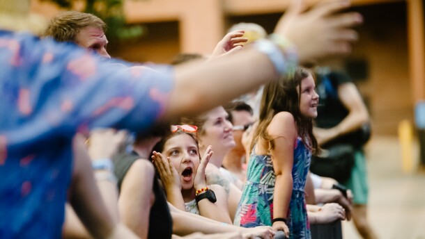 A group of children stand on a concert gate looking very excited about the band. 