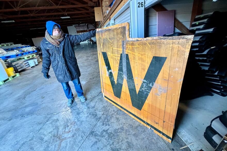 Alan Allsup, Iowa Wesleyan class of 1987, holds up the wood flooring from a now-dismantled gym.