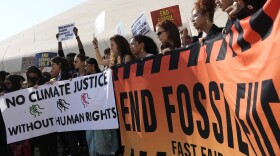 Demonstrators hold a sign reading "end fossil fuels" at the COP28 U.N. Climate Summit, Friday, Dec. 8, 2023, in Dubai, United Arab Emirates. (AP Photo/Peter Dejong)