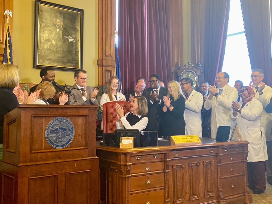 governor kim reynolds, doctors and lawmakers applaud a bill signing