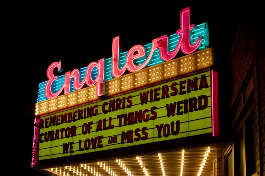 A neon theatre sign reads "remembering Chris Wiersema, curator of all things weird. We love and miss you." 