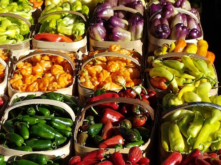 Several varieties of peppers in different colors sitting in baskets