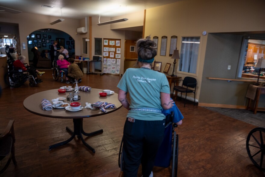 A worker at the Prairie View Nursing Home in Sanborn, Iowa, wheels a resident after lunch. The nursing home has faced chronic staffing shortages that were made worse by the COVID-19 pandemic.