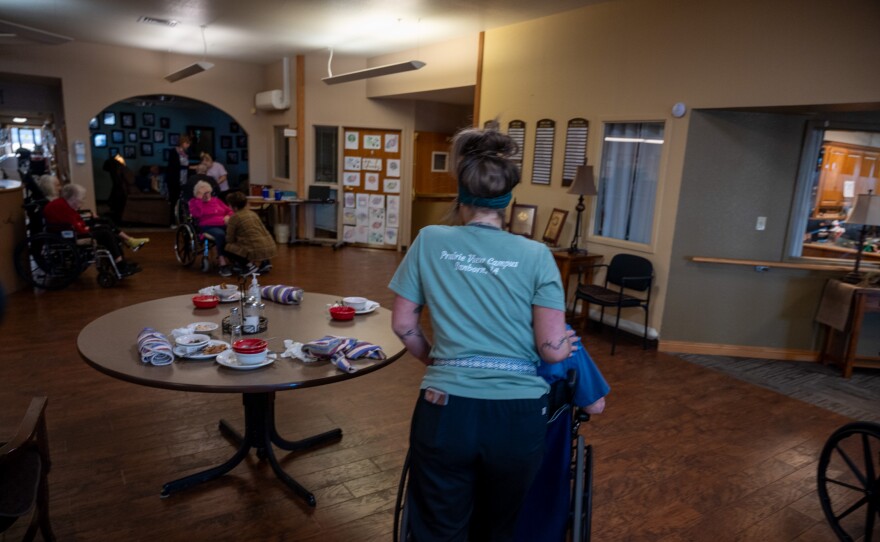 A worker at the Prairie View Nursing Home in Sanborn, Iowa, wheels a resident after lunch. The nursing home has faced chronic staffing shortages that were made worse by the COVID-19 pandemic.