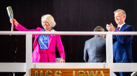  Former Iowa First Lady Christie Vilsack wears a pink pantsuit and holds up the christening champagne bottle.