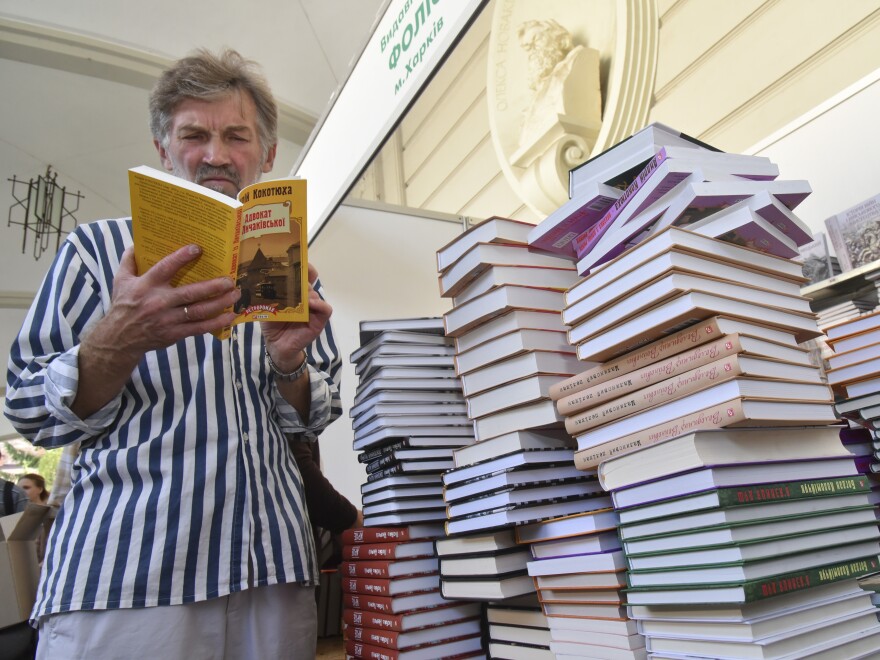 A visitor reads a book at a book fair during a Publishers Forum in Lviv, Ukraine, Wednesday, Sept. 19, 2018. A regional council in western Ukraine had passed a motion to ban all Russian-language books, films and songs in the region.