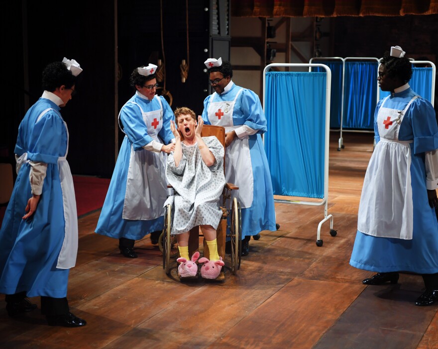 man in a wheelchair surrounded by doctors on an opera stage