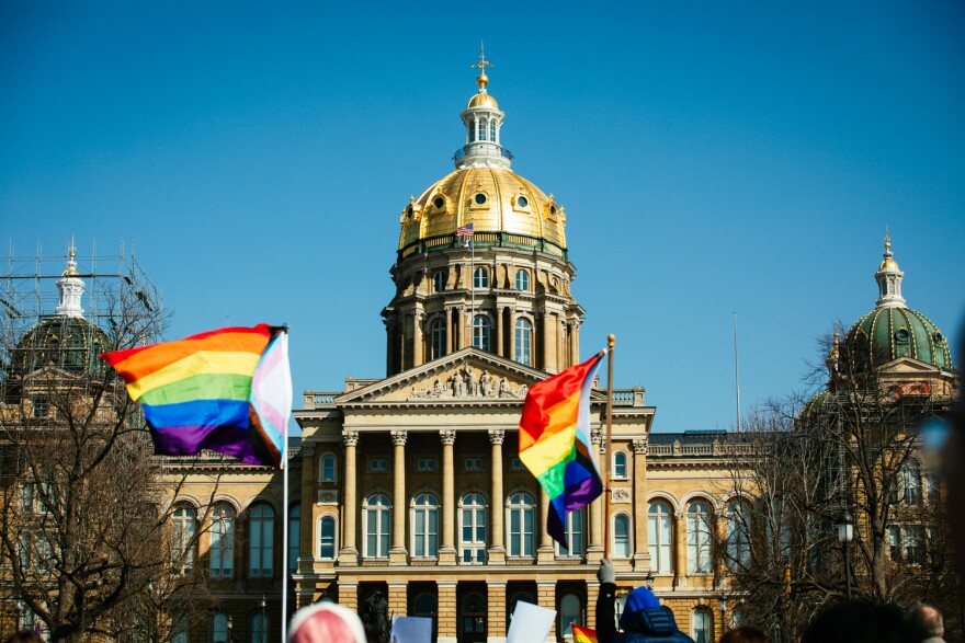 Rainbow pride flags wave in front of the Iowa Statehouse.