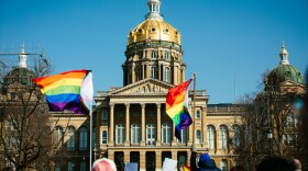 Rainbow pride flags wave in front of the Iowa Statehouse.