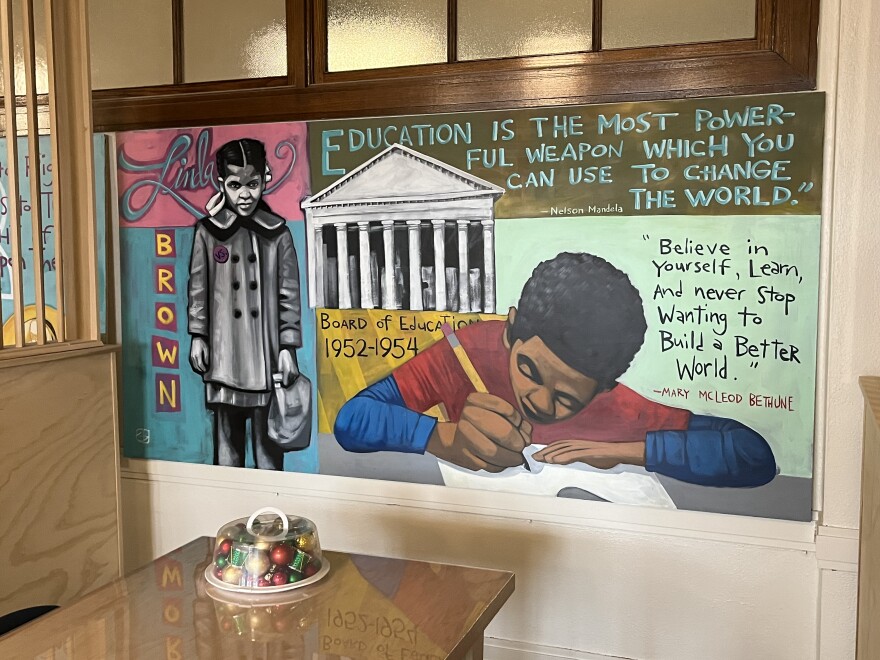 A mural representing Brown vs. Board of Education, and a child writing.