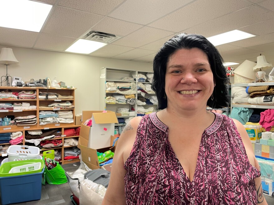 Kerri True-Funk, director of the Des Moines Field Office of the U.S. Committee for Refugees and Immigrants, stands in front of donation supplies at the main office. USCRI helps refugees settle into Iowa by providing some of the necessary equipment for a comfortable transition.