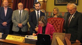 Gov. Kim Reynolds signed the AEA bill in her office with dozens of lawmakers and staffers on hand for the ceremony.