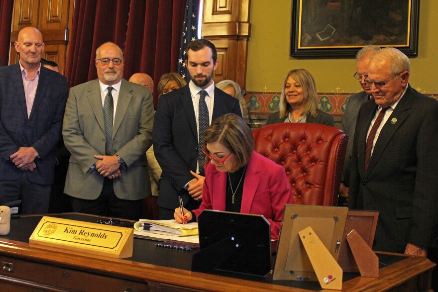 Gov. Kim Reynolds signed the AEA bill in her office with dozens of lawmakers and staffers on hand for the ceremony.