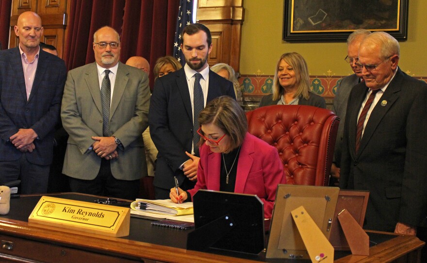 Gov. Kim Reynolds signed the AEA bill in her office with dozens of lawmakers and staffers on hand for the ceremony.