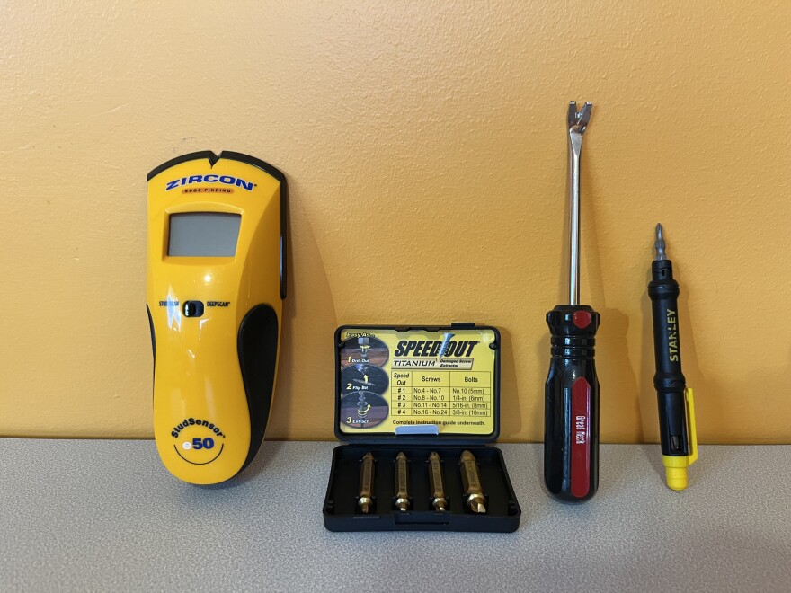 a stud finder tool, drill bits, and screwdrivers on a table